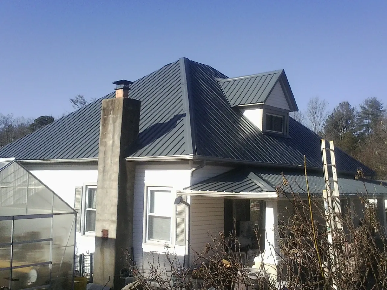 Dark blue standing seam metal roof on a white farmhouse with dormer — Slate & Tile Roof Repair by Roofing Brothers in Budd Lake
