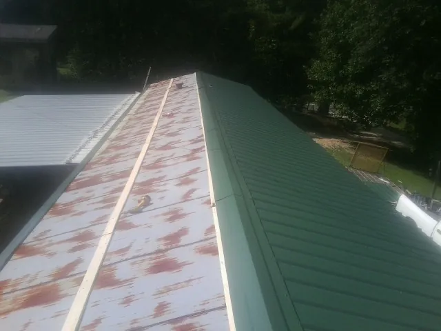 Old rusted panels beside newly installed green metal roofing — Wind Damage Roof Repair by Roofing Brothers in Budd Lake