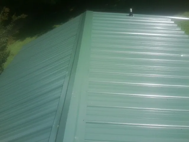 New green metal panels meeting at the ridge of a roof — Flat Roof Repair work by our crew in Budd Lake