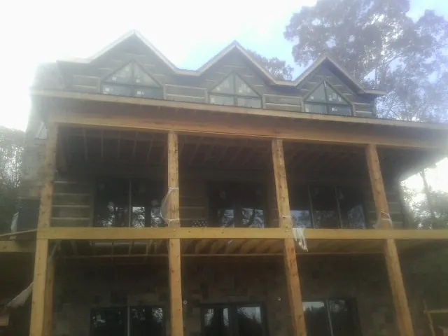 Dormers and porch framing on a large log home under construction — Roof Coating work by our crew in Budd Lake