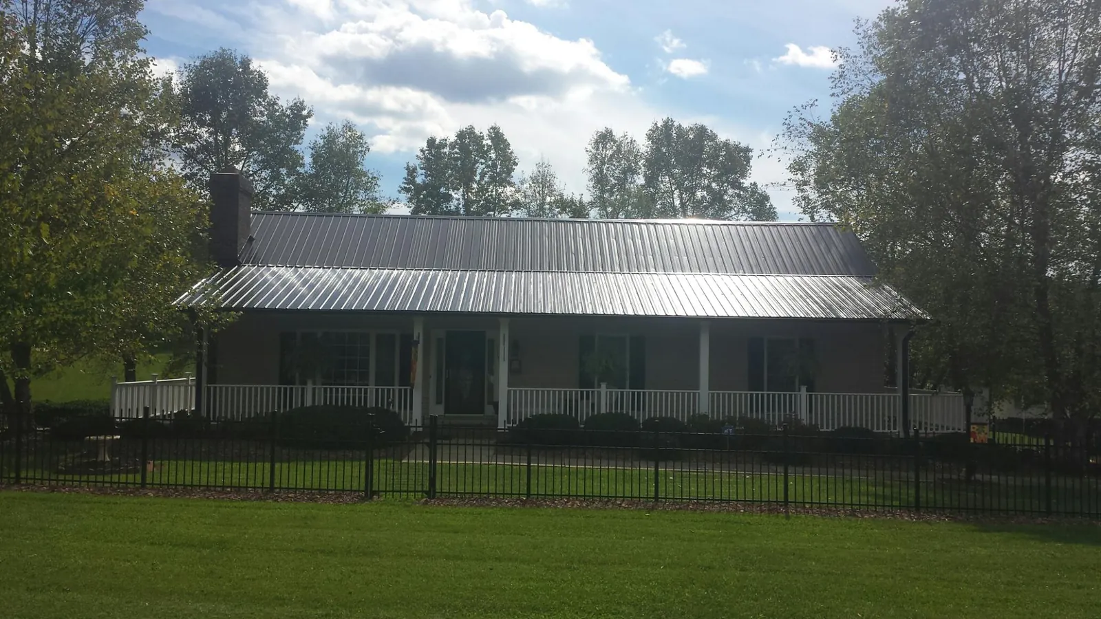 Gray metal roof on a brick ranch with a full width front porch — Gutter Guard Installation work by our crew in Budd Lake