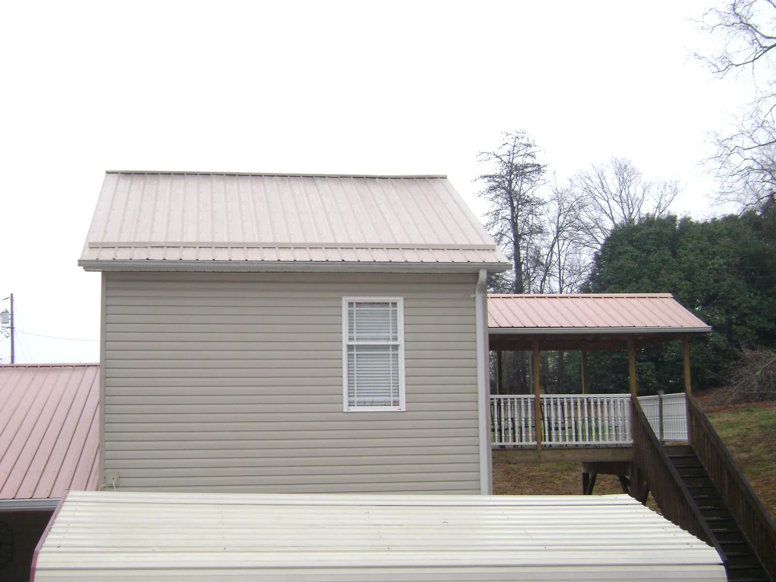 Tan metal roofs on a two story addition and attached porch, from a Roof Replacement job in Budd Lake