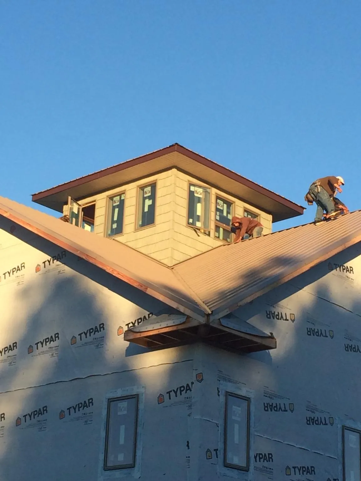 Roofers working around a rooftop cupola on a new metal roof at sunset — Roof Waterproofing in Budd Lake by Roofing Brothers